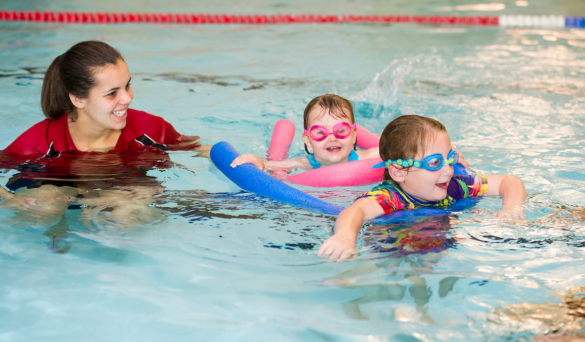 Children doing swimming lessons with swim instructor
