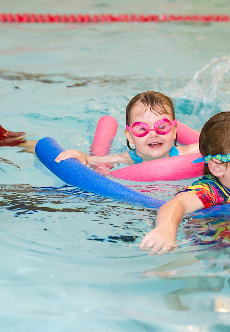 Children doing swimming lessons with swim instructor